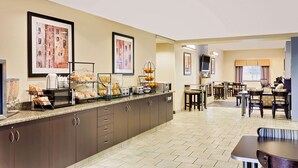 A hotel breakfast area with a buffet, dining tables, and chairs. - Microtel Inn & Suites by Wyndham Geneva (Geneva)