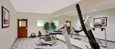 A fitness room with a treadmill, exercise bike, and a mirrored wall.