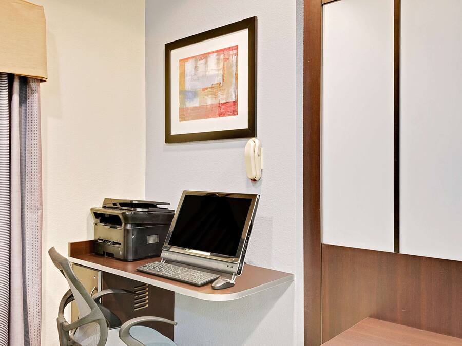 Une chambre d’hôtel équipée d’un bureau, d’un ordinateur portable, d’une imprimante et d’un téléphone.