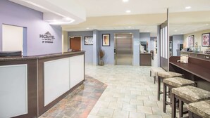 A reception area with a counter, seating, and a staircase leading to an upper floor. - Microtel Inn & Suites by Wyndham Geneva (Geneva)