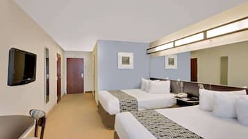 A hotel room with two beds, a desk, a chair, a TV, and a mirror.