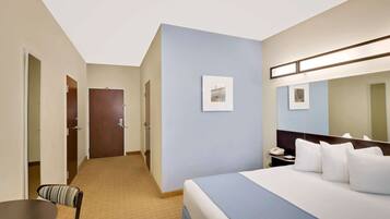 Una habitación de hotel con cama, escritorio, silla y puerta.
