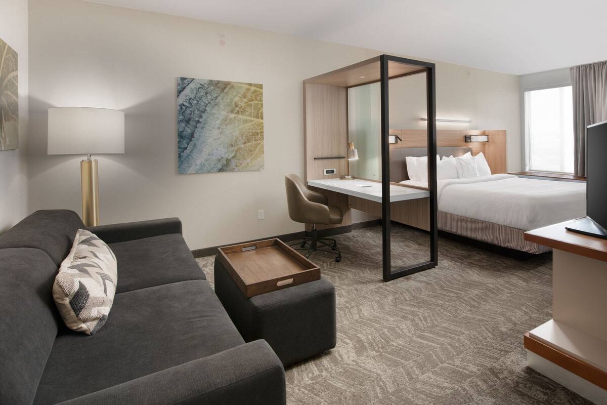 A hotel room with a sofa, desk, and bed.