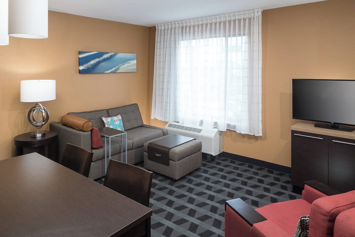 Ein Hotelzimmer mit einer Couch, einem Sessel und einem Fernseher.