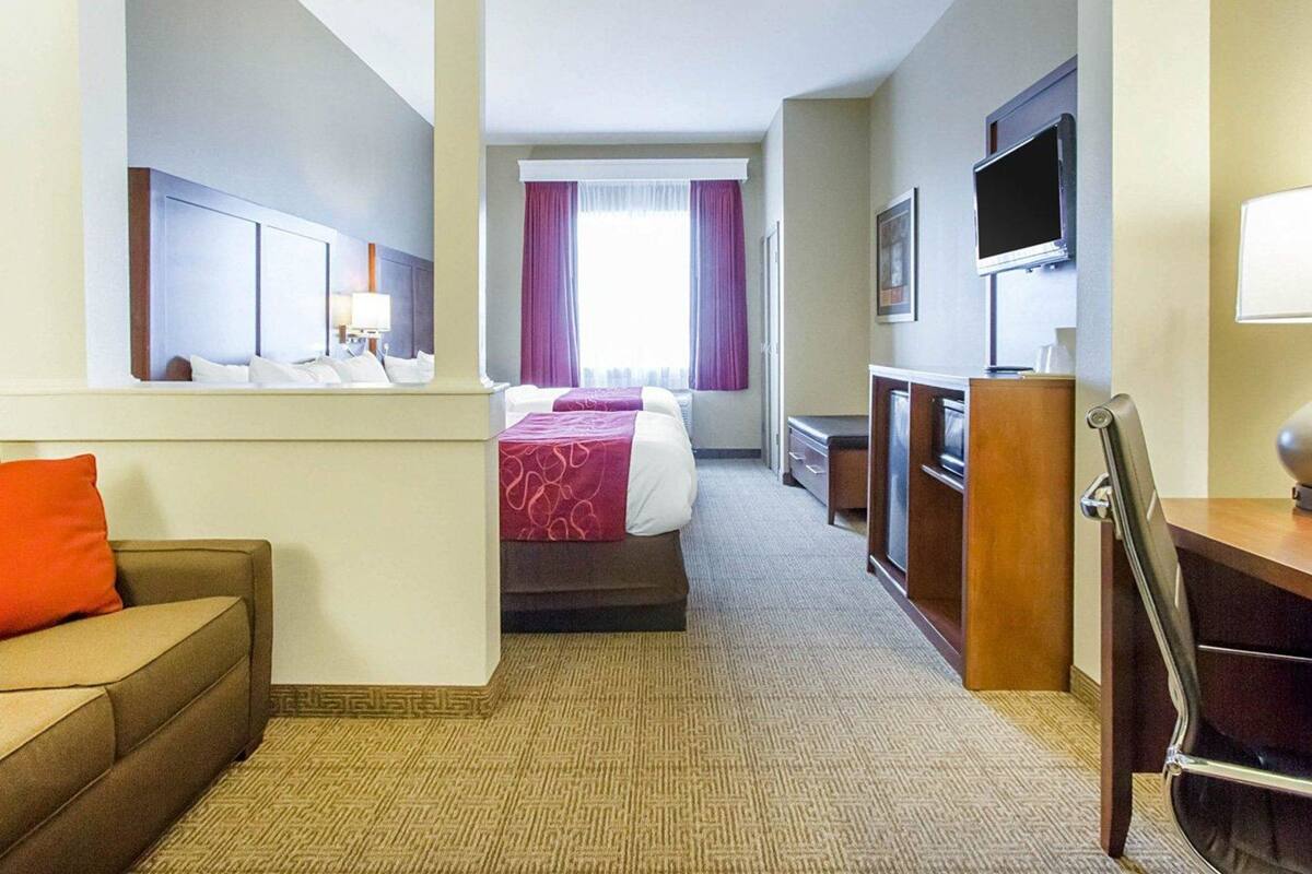 A hotel room with a bed, a desk, a TV, and a couch.