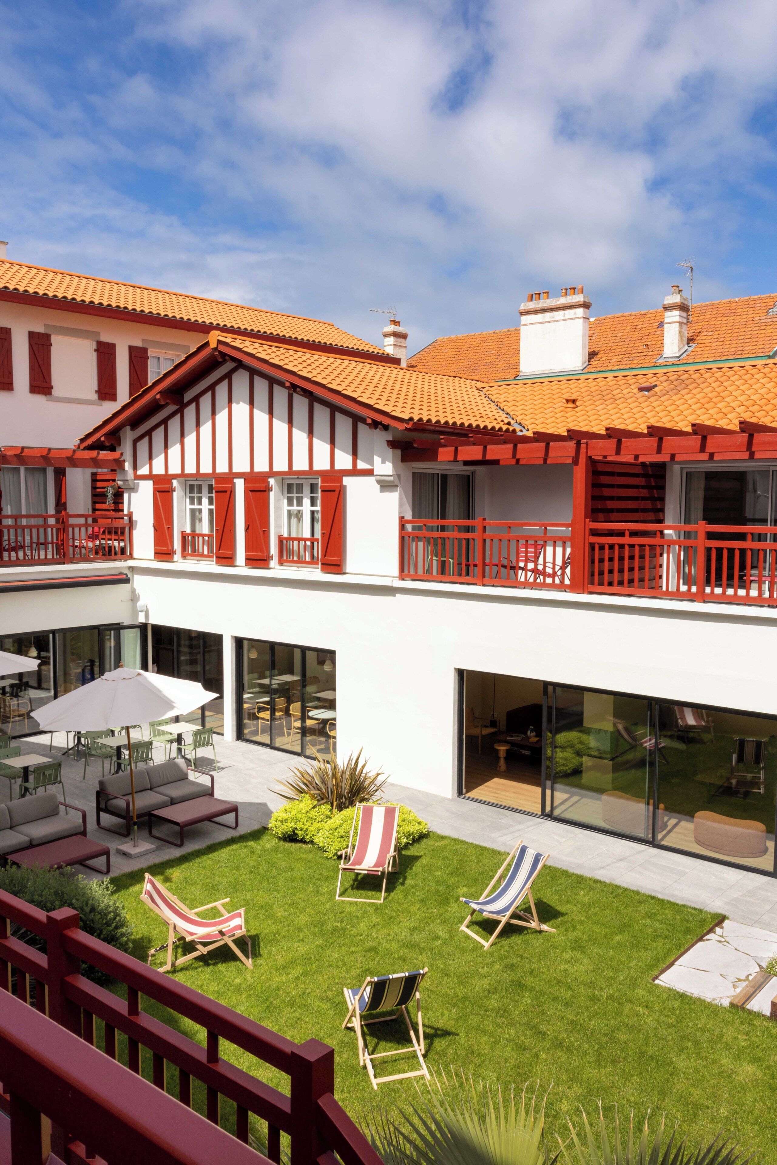 A two-story building with a balcony, outdoor seating, and a well-maintained lawn.