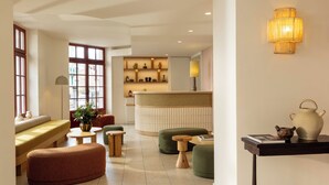 A modern interior with a seating area, a reception desk, and a wall-mounted light fixture. - Hôtel Kemaris (Biarritz)