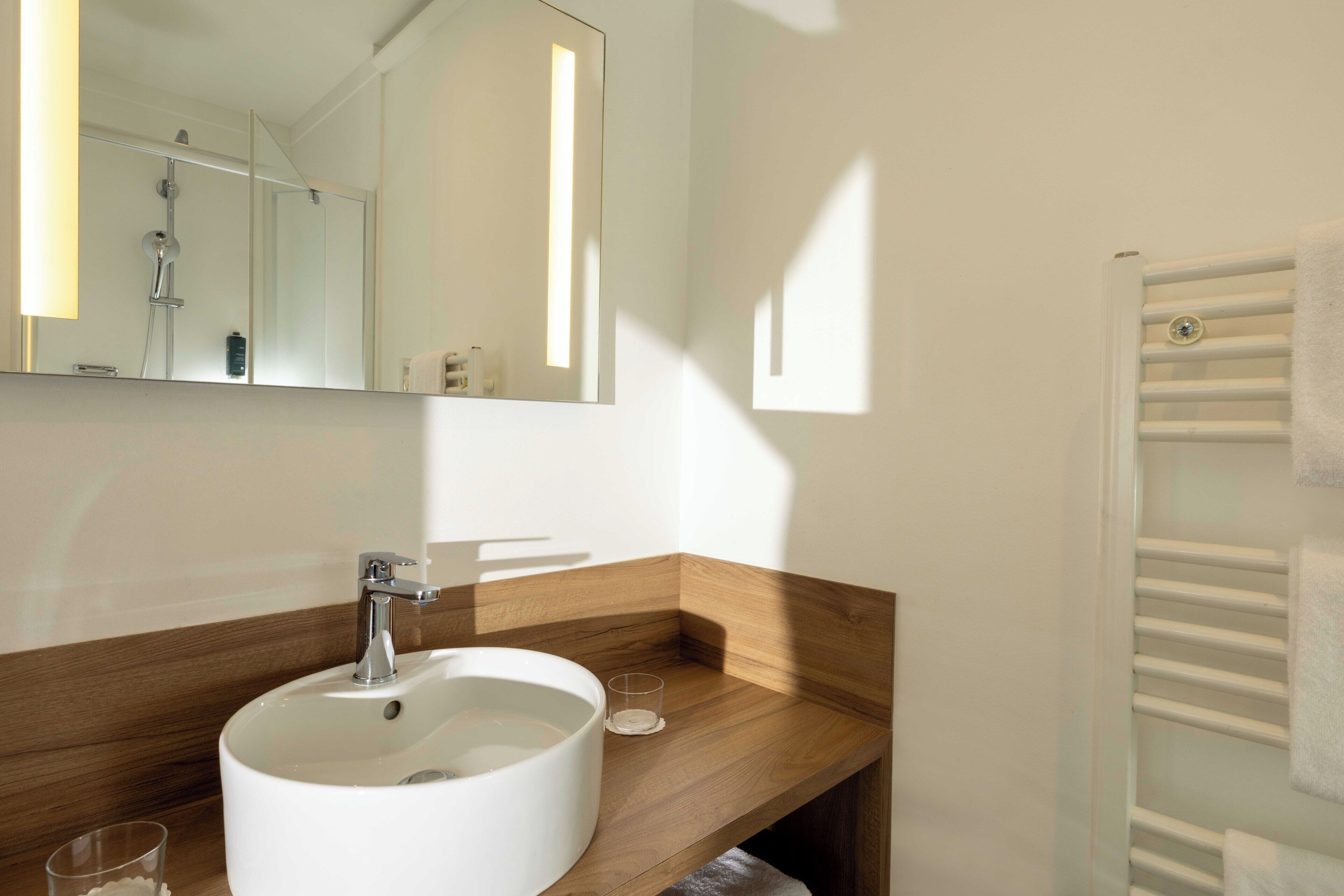 A bathroom with a white sink, mirror, and towel rack.