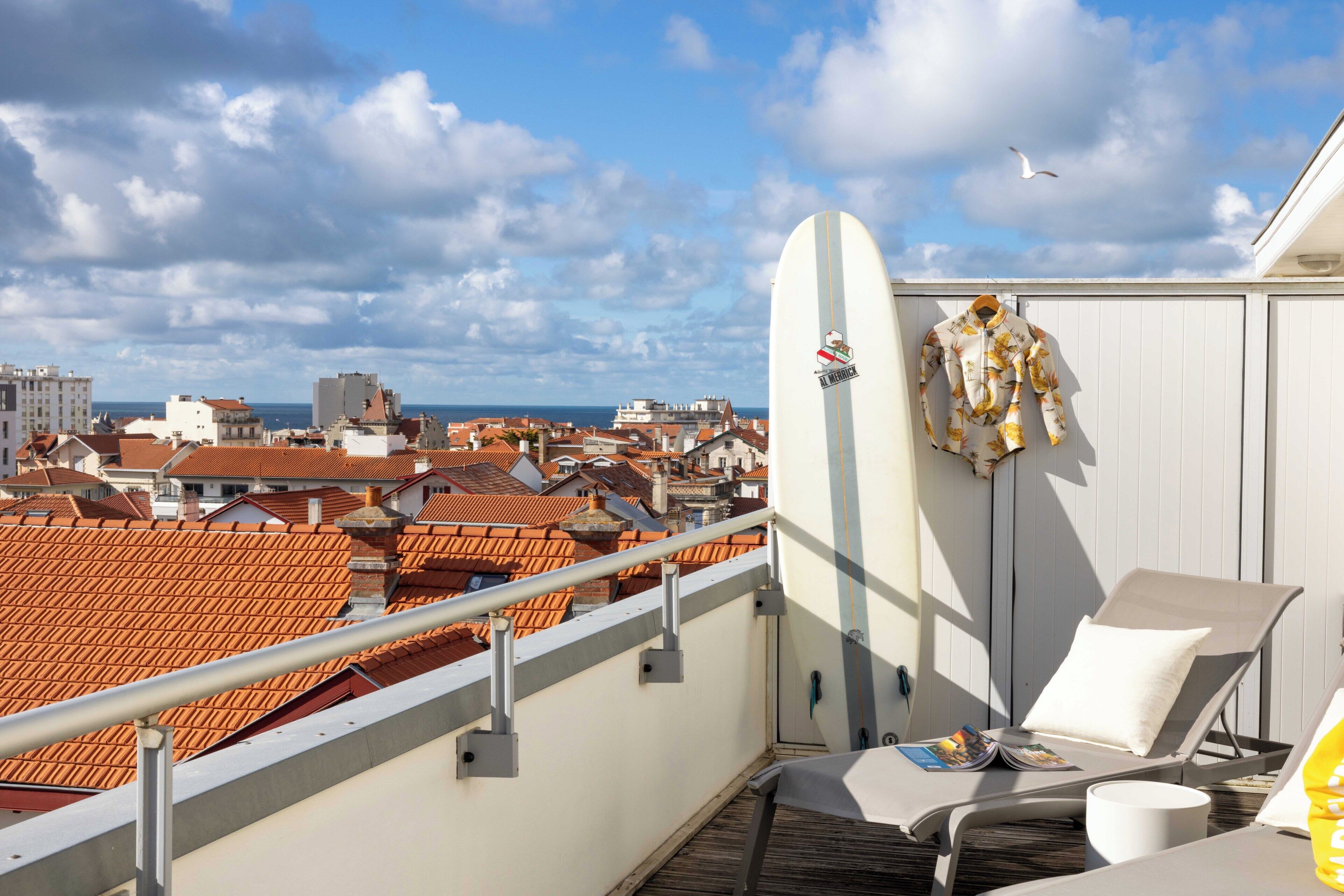 A balcony with a white surfboard, a lounge chair, and a magazine.