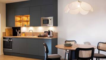 A modern kitchen with dark cabinetry, a built-in microwave, and a round dining table with chairs.