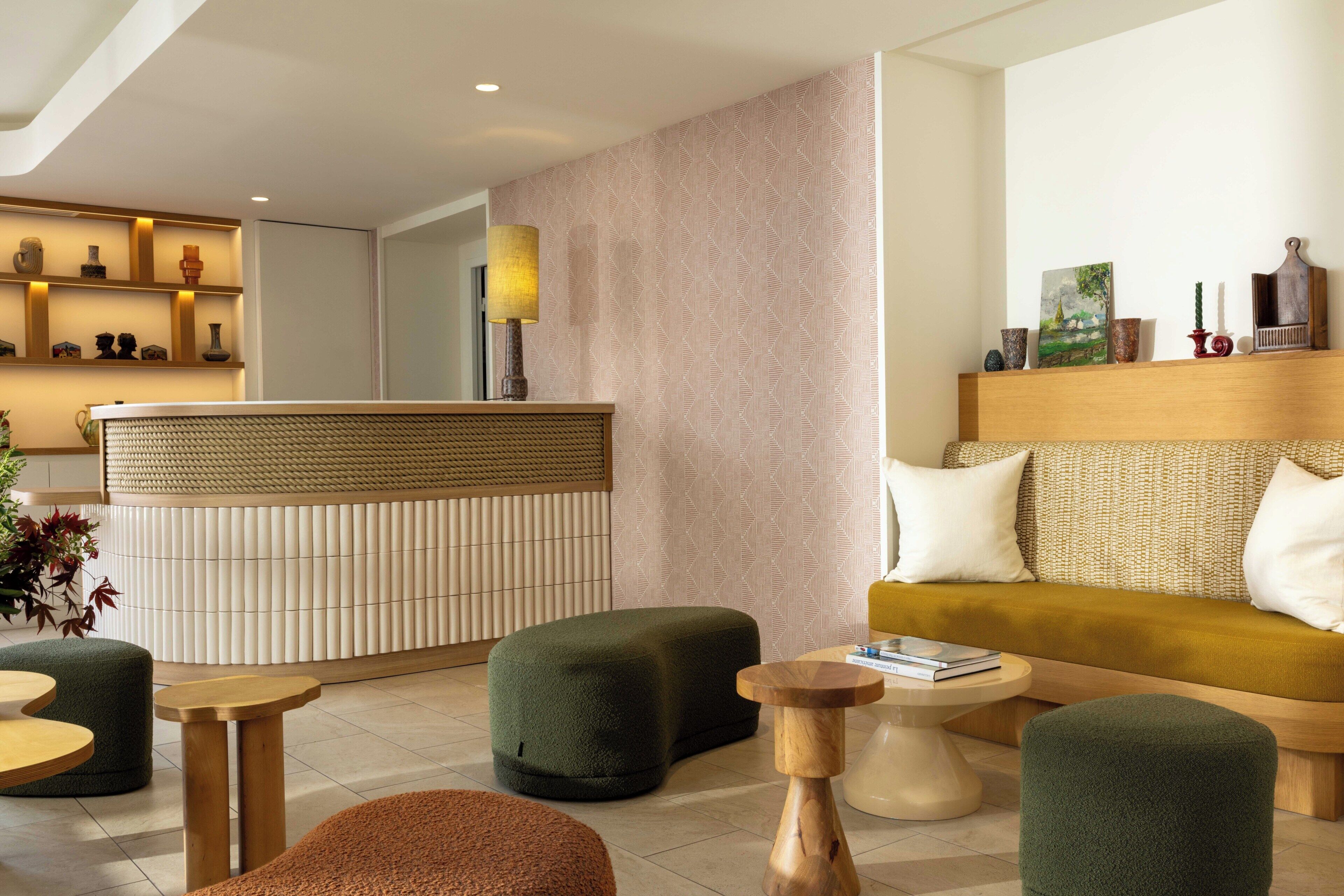 A modern lobby with a reception desk, green seating, and a sofa with white cushions.