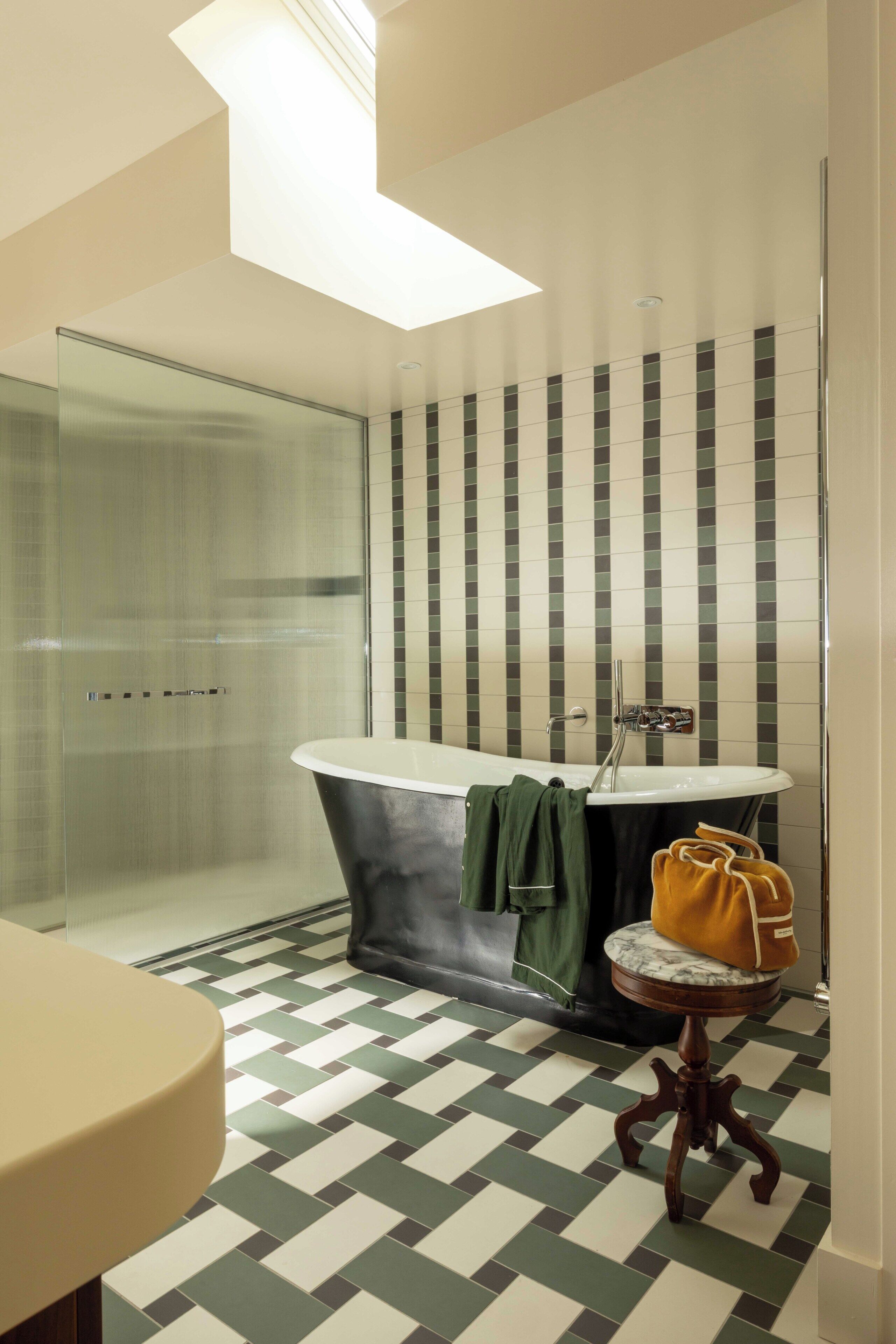 Un baño con cabina de ducha de vidrio, una bañera independiente y un piso con diseño de cuadros.