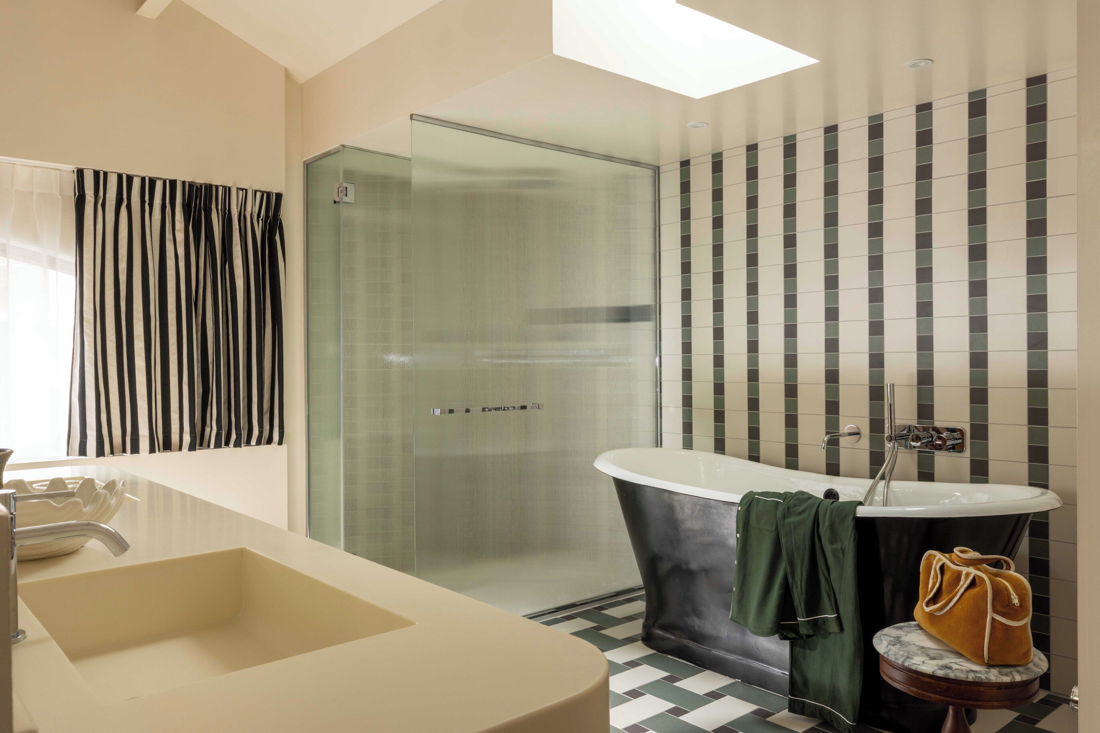 Un baño moderno con cabina de ducha de vidrio, una bañera independiente y un lavamanos grande.