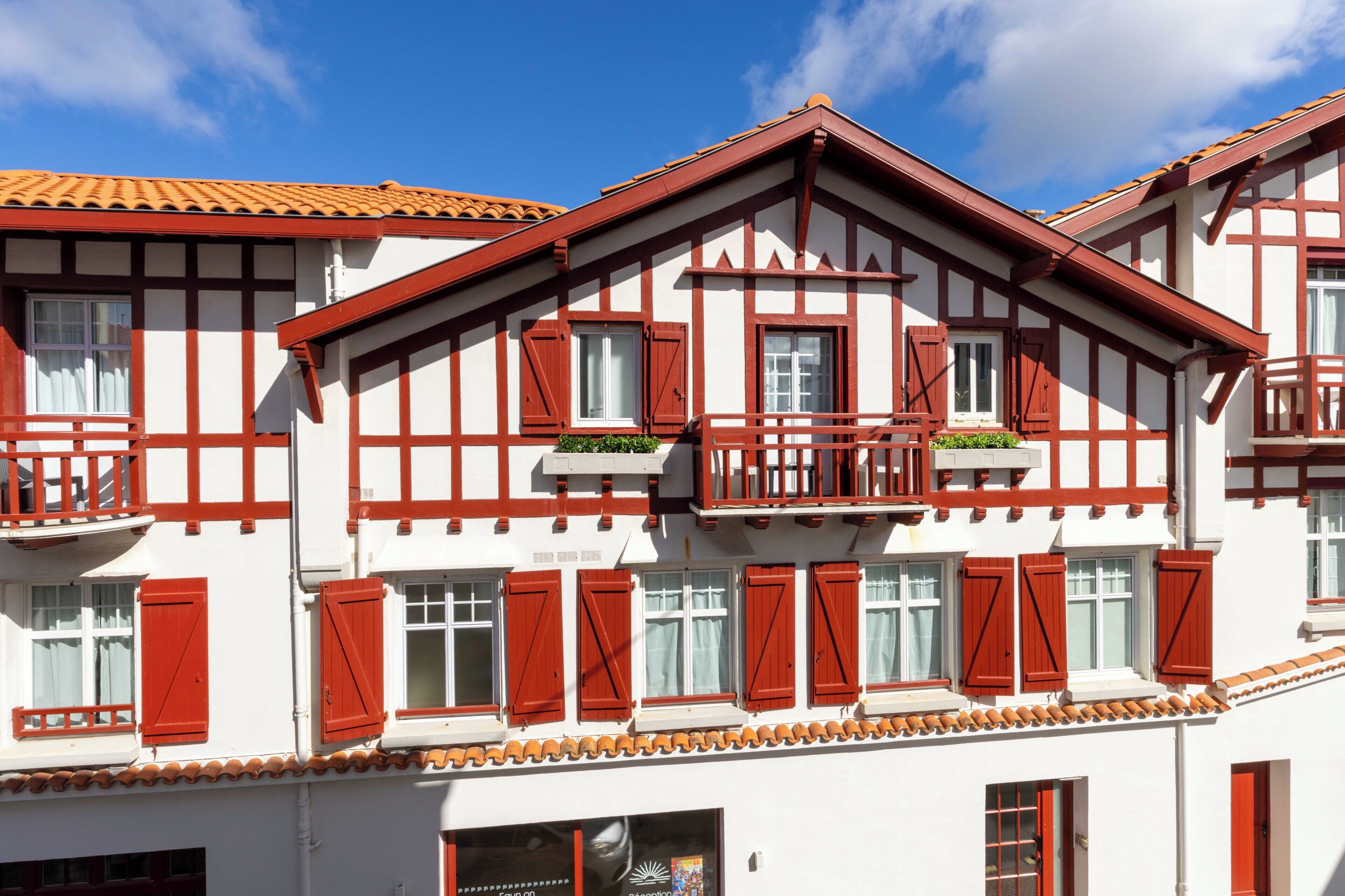 A traditional building with multiple windows, balconies, and a tiled roof.