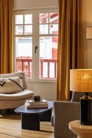 Una habitación con sofá, una mesita, una lámpara y un ventanal con cortinas.