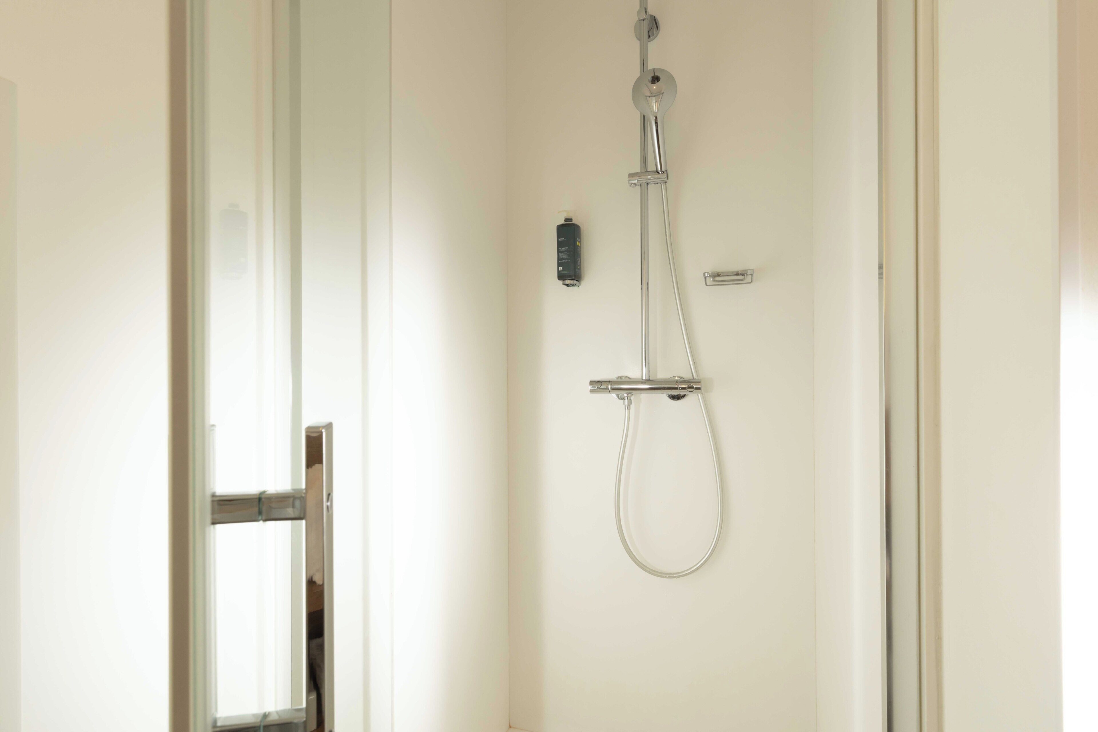 A bathroom with a shower, a toilet, and a glass door.