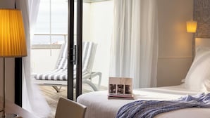 A hotel room with a bed, a chair, a laptop, and a view of the outside. - Hôtel Kemaris (Biarritz)