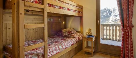 A wooden bunk bed room with a window and curtains.