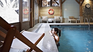 A pool area with wooden beams, a lifebuoy, and a clock on the wall. - CGH Résidences & SPAS Le Ruitor (Sainte-Foy-Tarentaise)