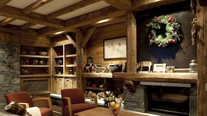 A cozy cabin interior with a stone fireplace, wooden shelves, and a festive wreath. - CGH Résidences & SPAS Le Ruitor (Sainte-Foy-Tarentaise)