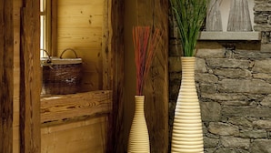 A wooden interior with a stone wall and a large vase with plants. - CGH Résidences & SPAS Le Ruitor (Sainte-Foy-Tarentaise)