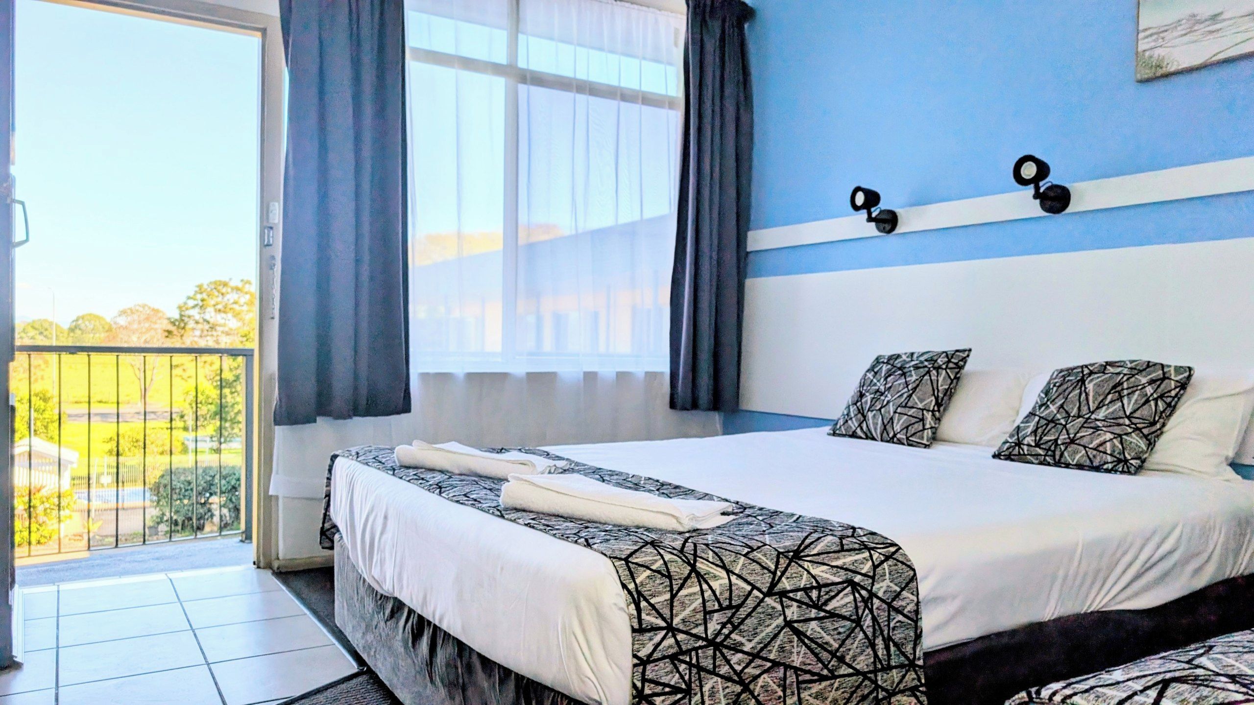 A hotel room with a bed, curtains, a window, and a view of the outside.