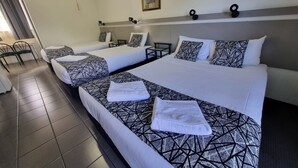 A hotel room with two beds, a desk, and a chair.