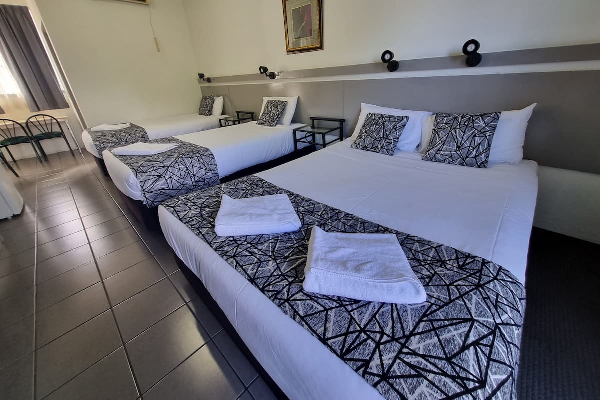 A hotel room with two beds, a desk, and a chair.