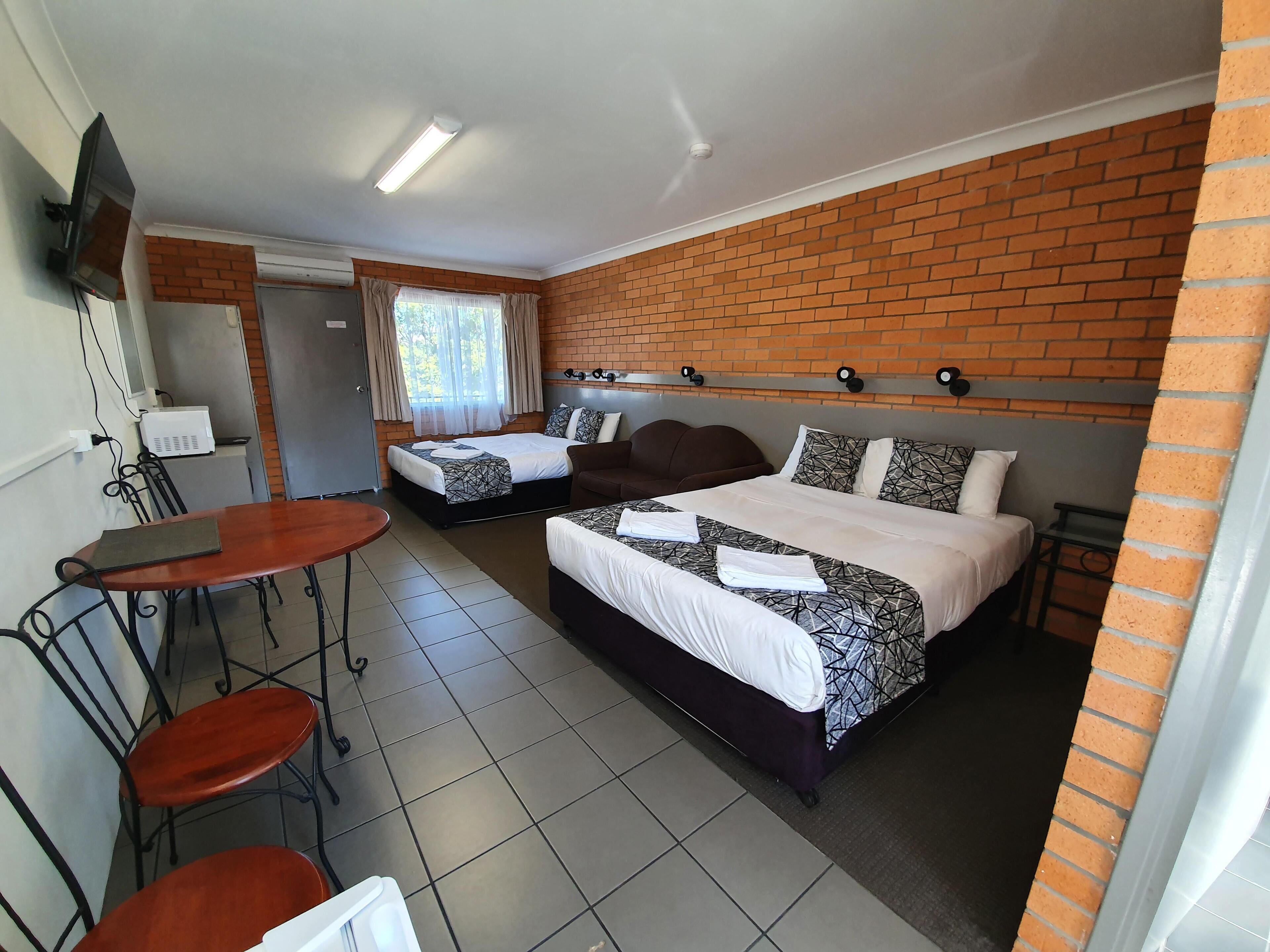 Quarto de hotel com duas camas, uma mesa de jantar e cadeiras.