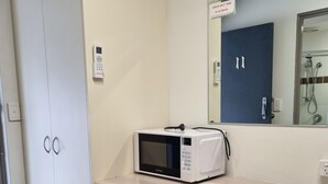 Une petite cuisine équipée d’un four à micro-ondes, d’un petit réfrigérateur et d’un meuble avec un miroir au-dessus.