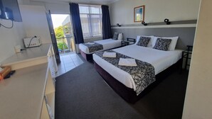 A hotel room with two beds, a flat-screen TV, a microwave, and a balcony with curtains.