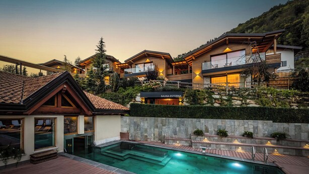Un resort moderno con piscina, terraza de madera y varias habitaciones con balcones.