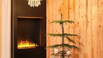 Un tavolo da pranzo in legno con un lampadario, un camino e una pianta decorativa con candele.