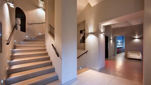A modern interior with a staircase, light fixtures, and a seating area. - Red and Blue Design Hotel Prague (Prague)