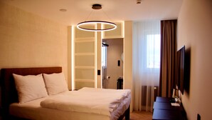 A hotel room with a large bed, a desk, a TV, and a circular light fixture. - Red and Blue Design Hotel Prague (Prague)