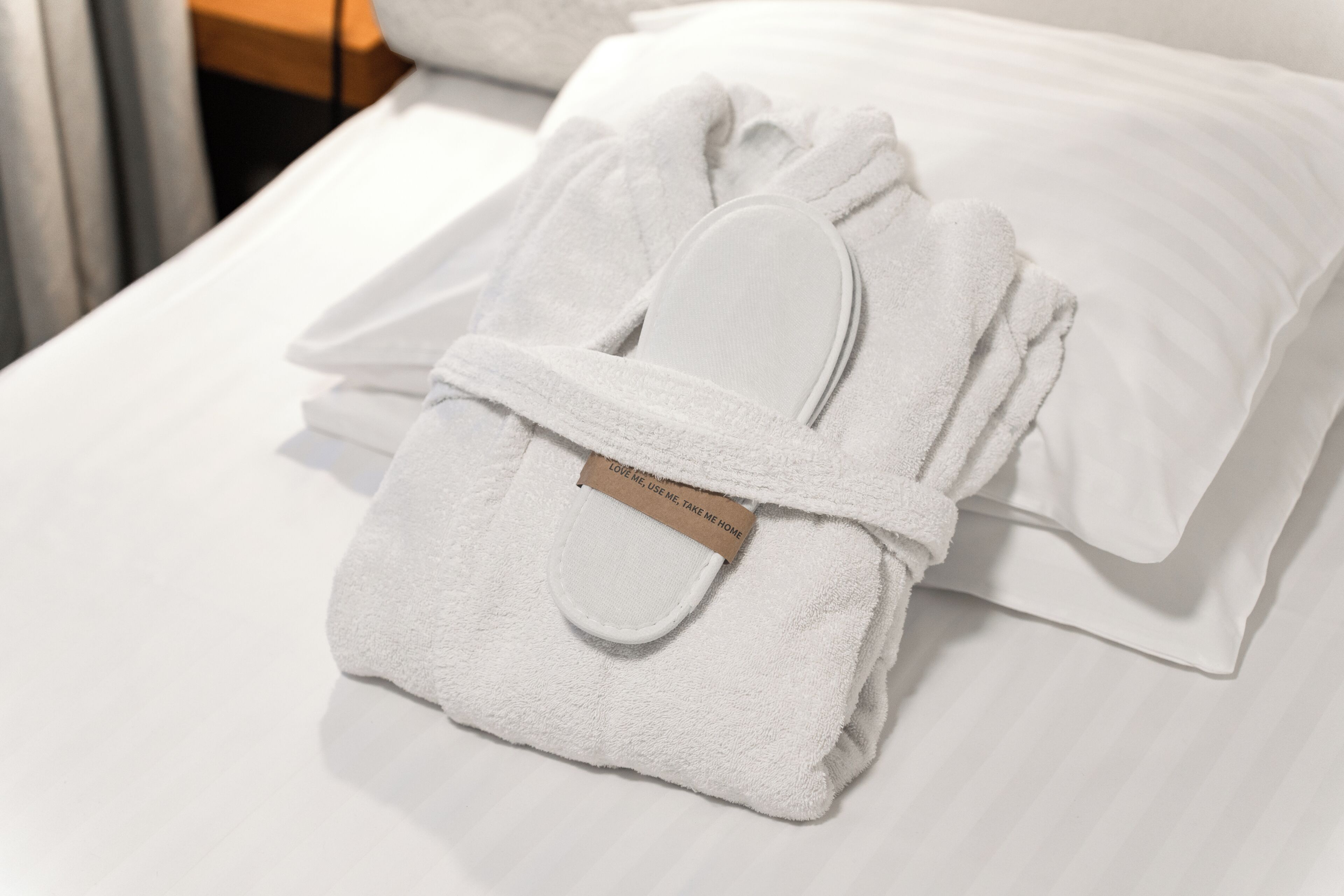 A neatly folded white towel with a tag on a bed.