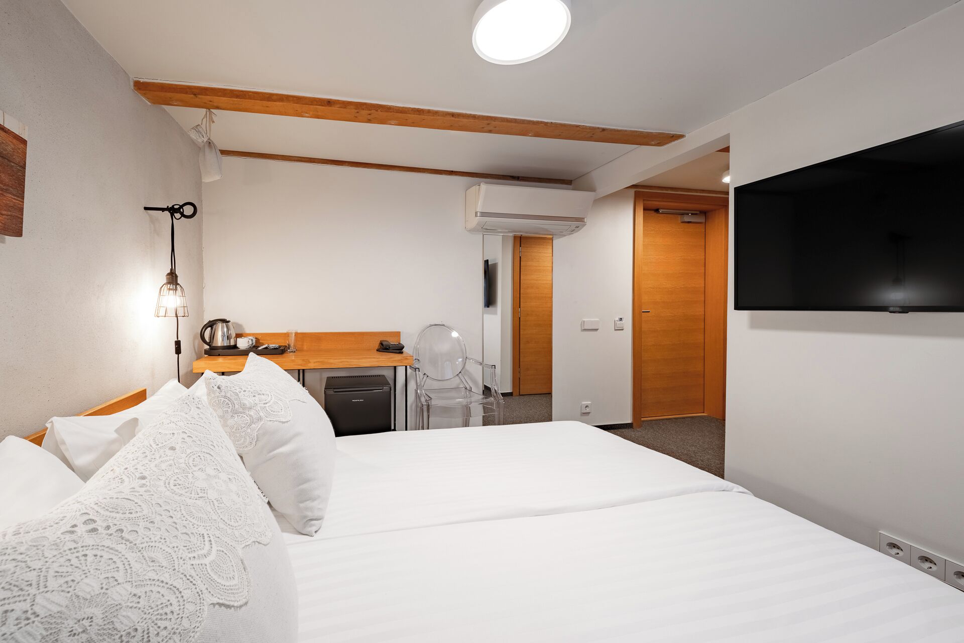 Hotellihuone, jossa on sänky, kirjoituspöytä, jossa on vedenkeitin, tuoli, televisio ja ilmastointilaite.