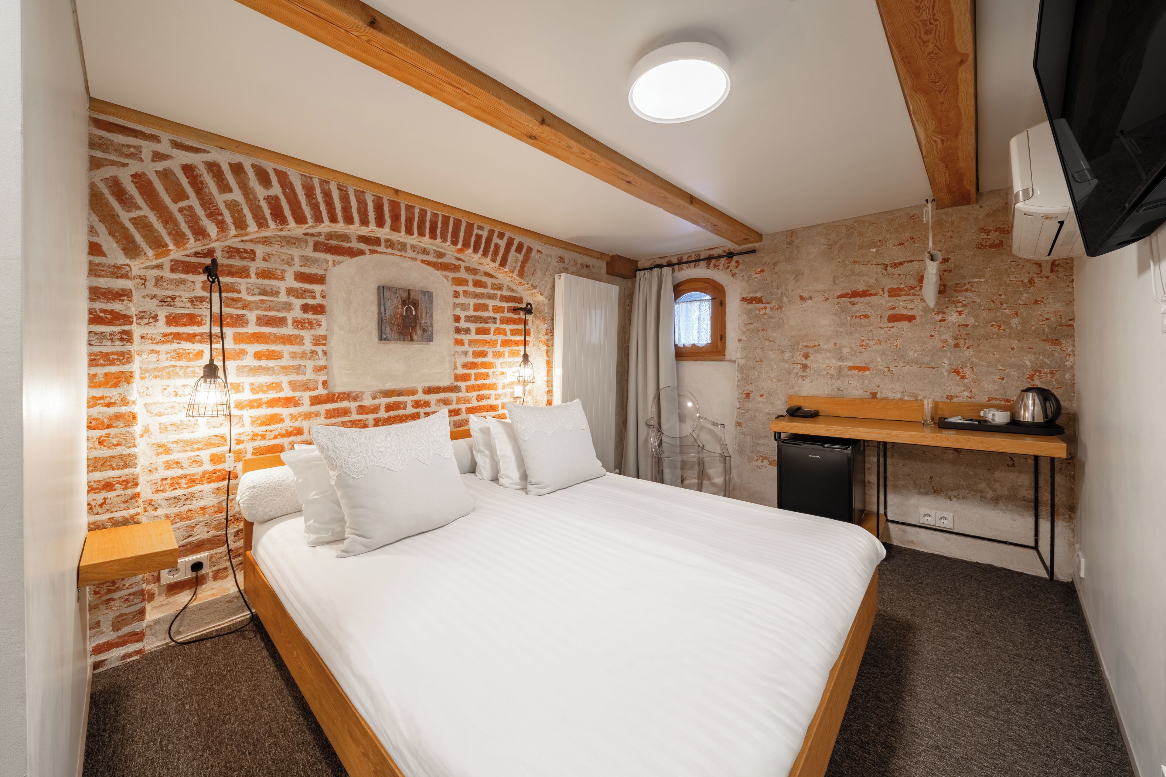 Une pièce avec un mur en briques, un lit, un bureau et une petite kitchenette.