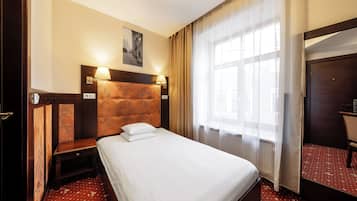 Une chambre d’hôtel comprenant un lit, des lampes de chevet, une table de chevet, une fenêtre avec des rideaux et un miroir.