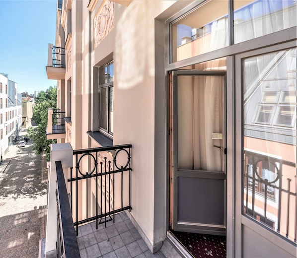 A modern apartment with a balcony, large windows, and a view of the street. - Rixwell Old Riga Palace Hotel (Riga)
