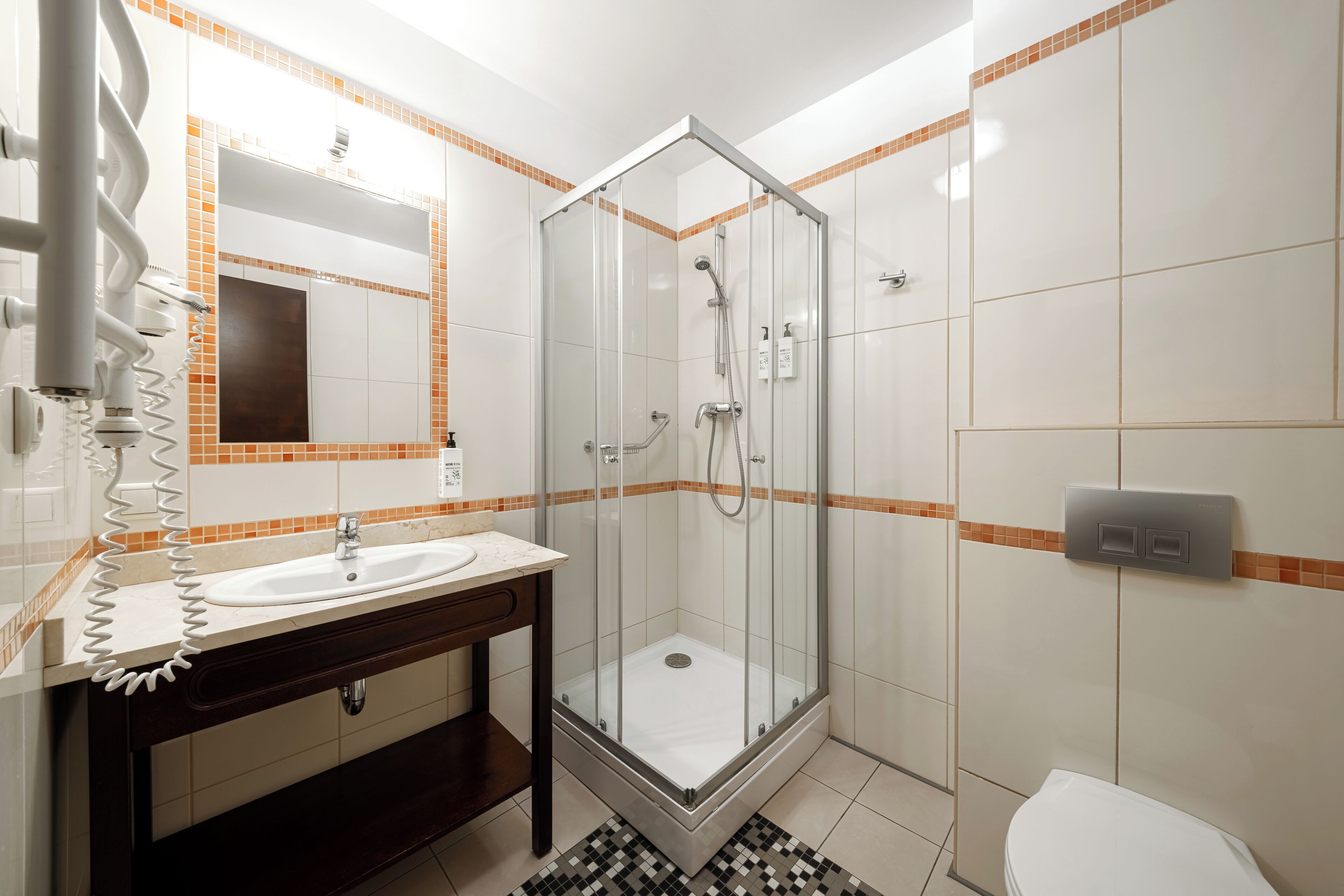 Un baño con cabina de ducha de vidrio, lavabo con espejo e inodoro.