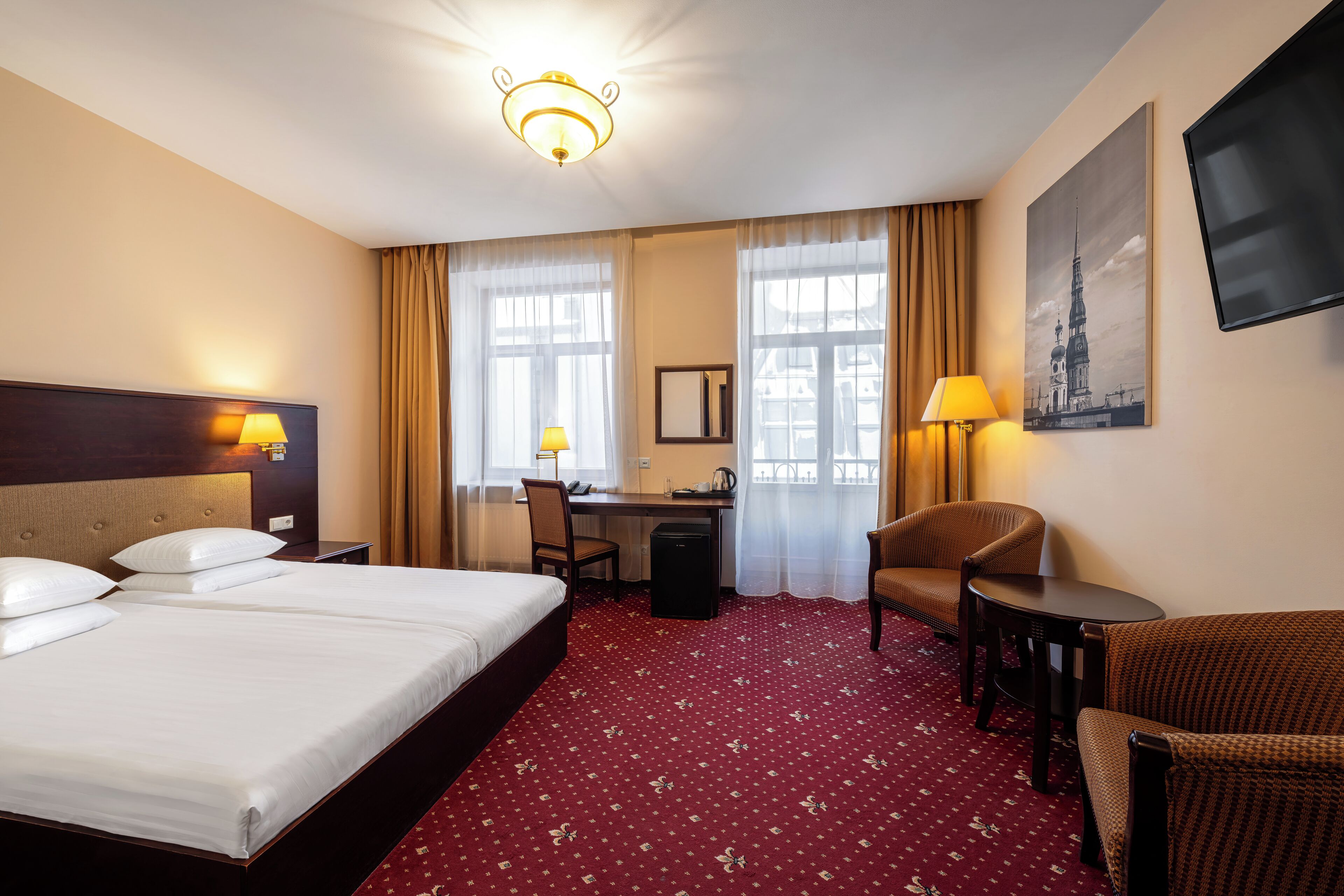 A hotel room with a bed, desk, chair, and a TV.