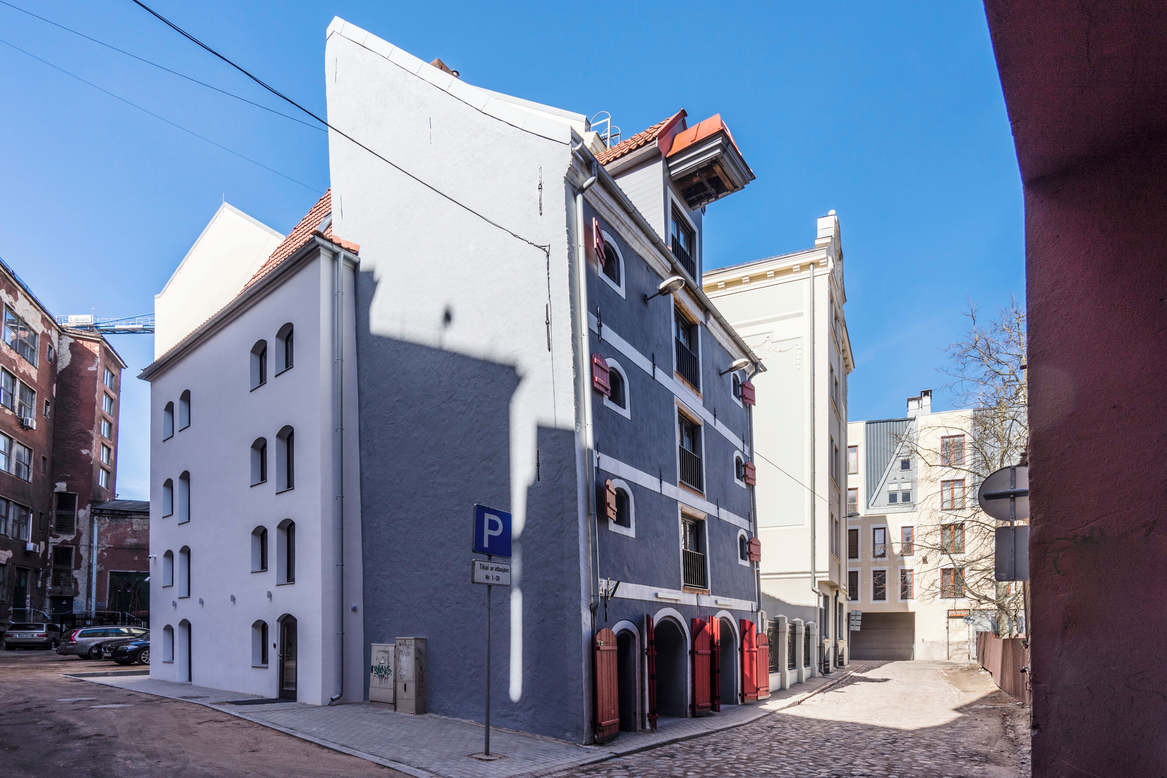 A building with a parking sign, a cobblestone street, and a clear blue sky.