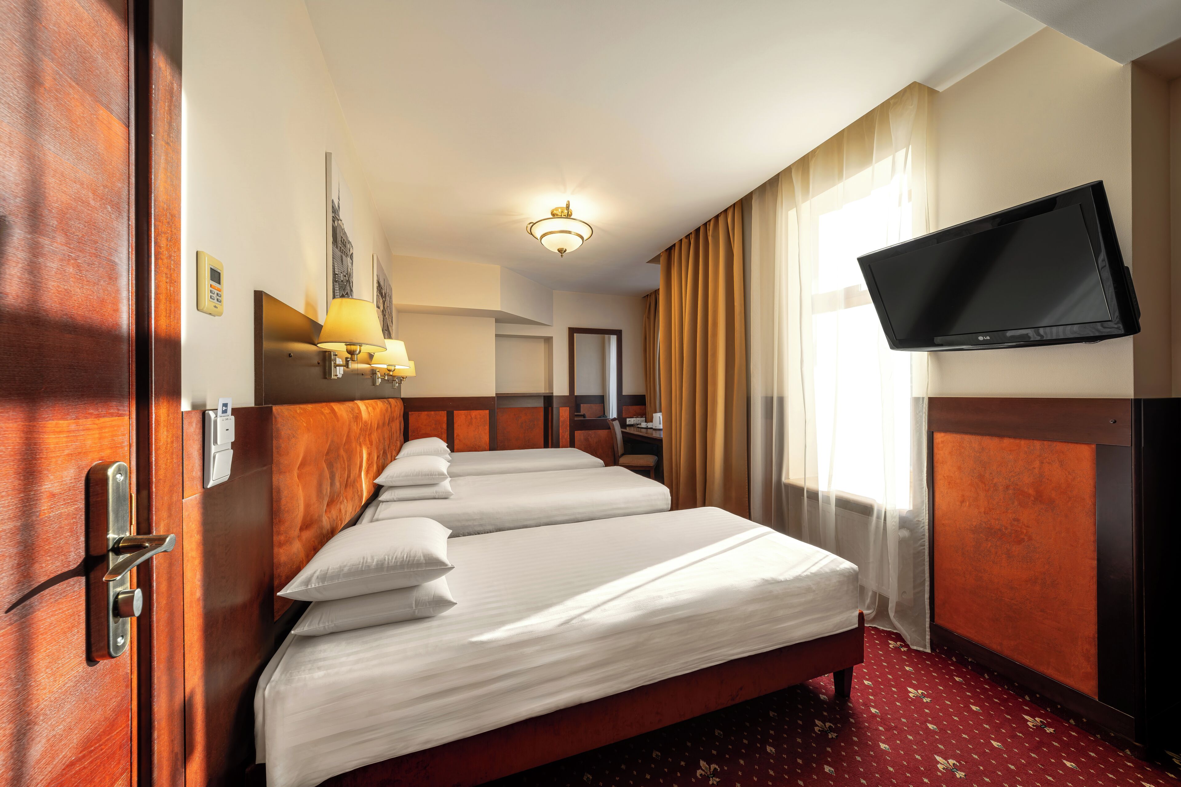 A hotel room with a large bed, a television mounted on the wall, and a wooden door.