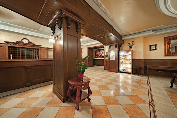 Eine Lobby mit Schachbrettfußboden, Holzmöbeln, einem Blumentopf und einem großen Spiegel.