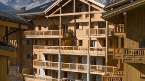 Un immeuble en bois à plusieurs étages, doté de balcons, de murs en pierre et surplombant un paysage montagneux.