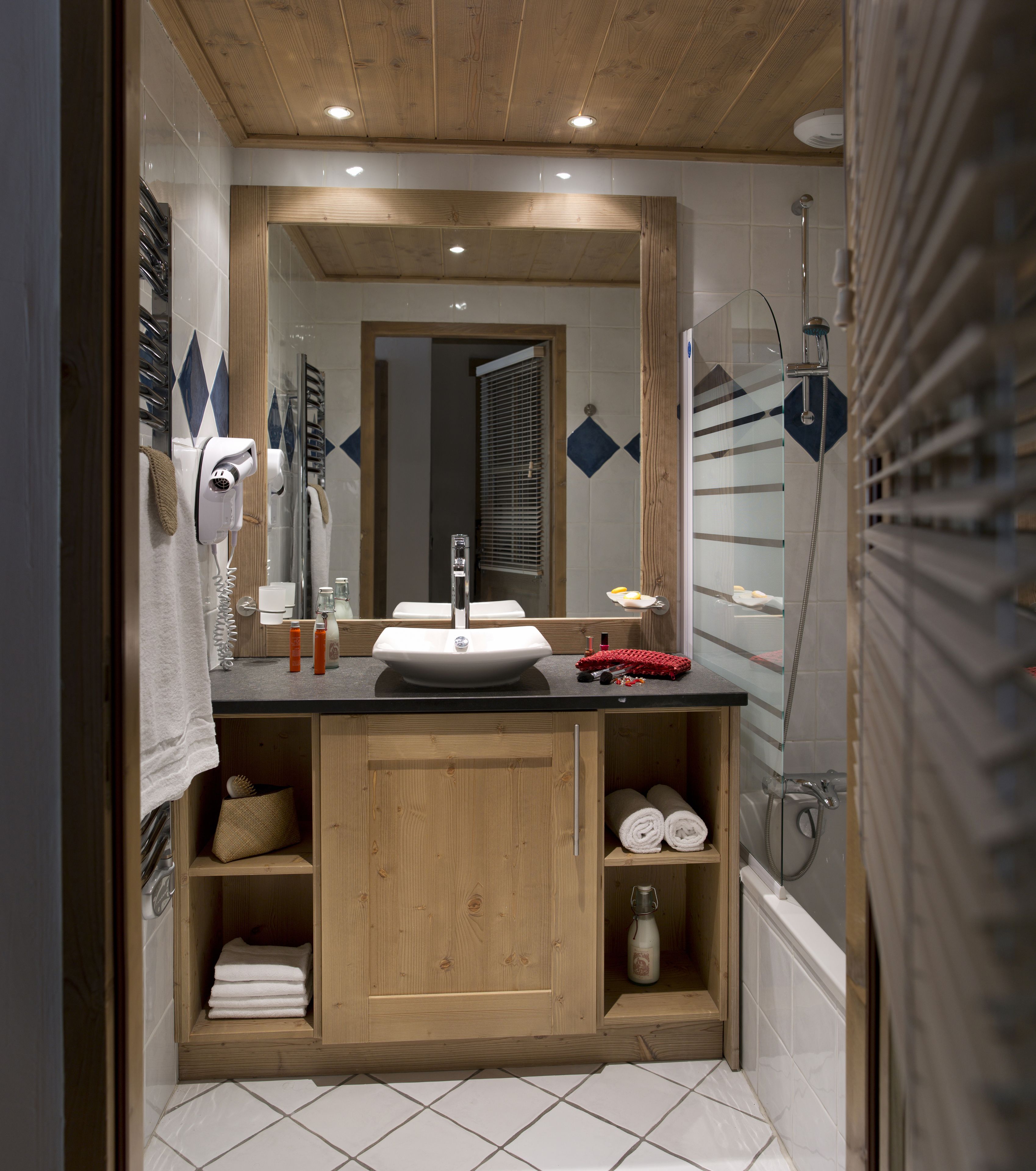 A modern bathroom with a wooden vanity, a large mirror, and a glass-enclosed shower.
