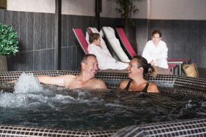 A couple in a hot tub with a tiled wall and a potted plant in the background. - CGH Résidences  Boutique Le Telemark (Tignes)