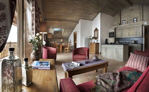 A spacious living room with a wooden ceiling, a dining area, and a kitchen with light-colored cabinets. - CGH Résidences  Boutique Le Telemark (Tignes)