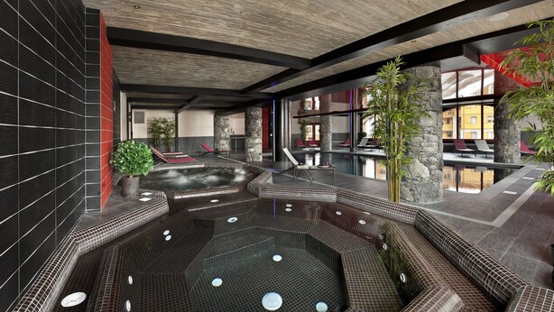 Un espace piscine intérieur moderne, doté de plusieurs bains à remous et de chaises longues.